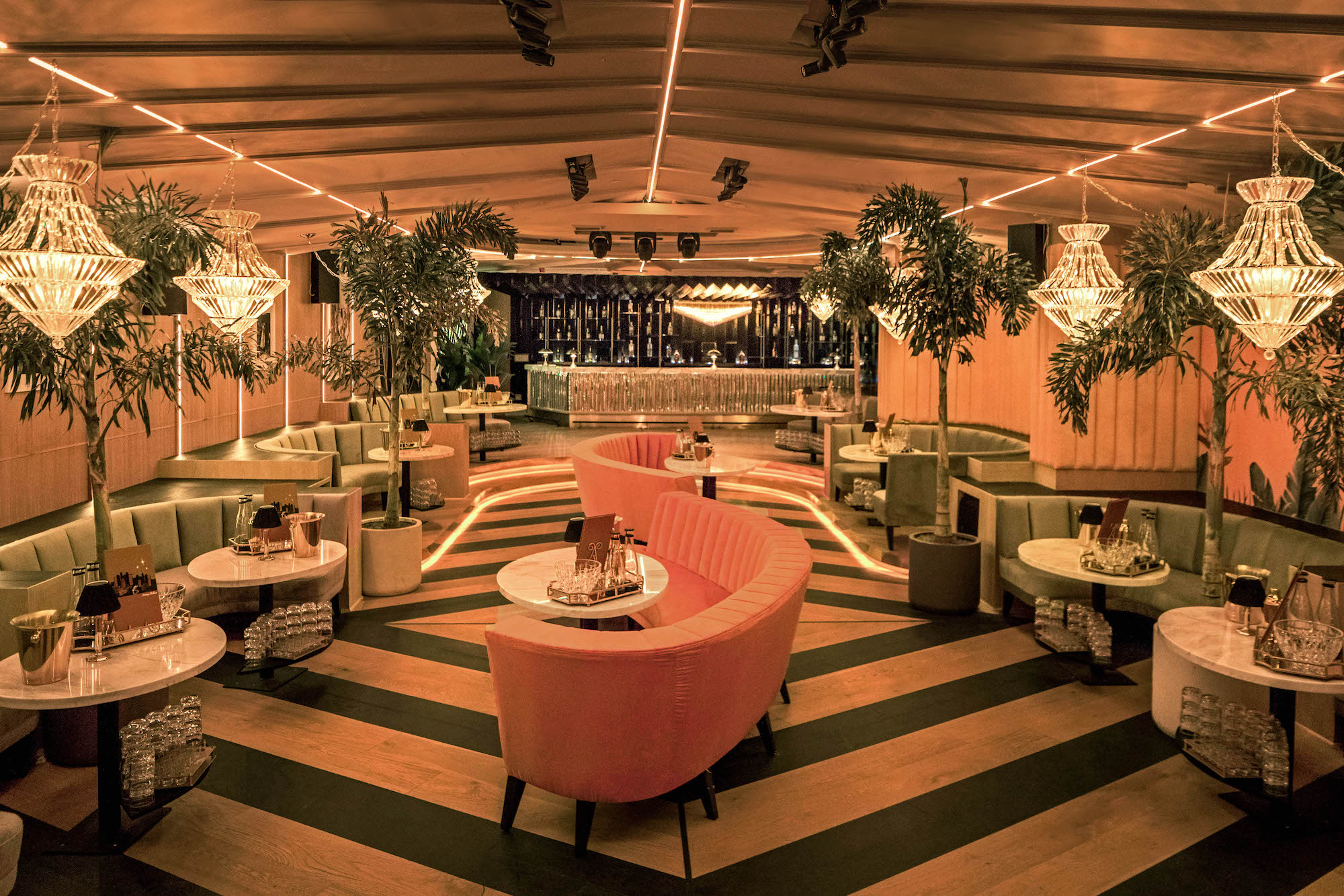A wide view of the Bootsy Bellows lounge with banquettes, greenery, and ceiling fixtures.